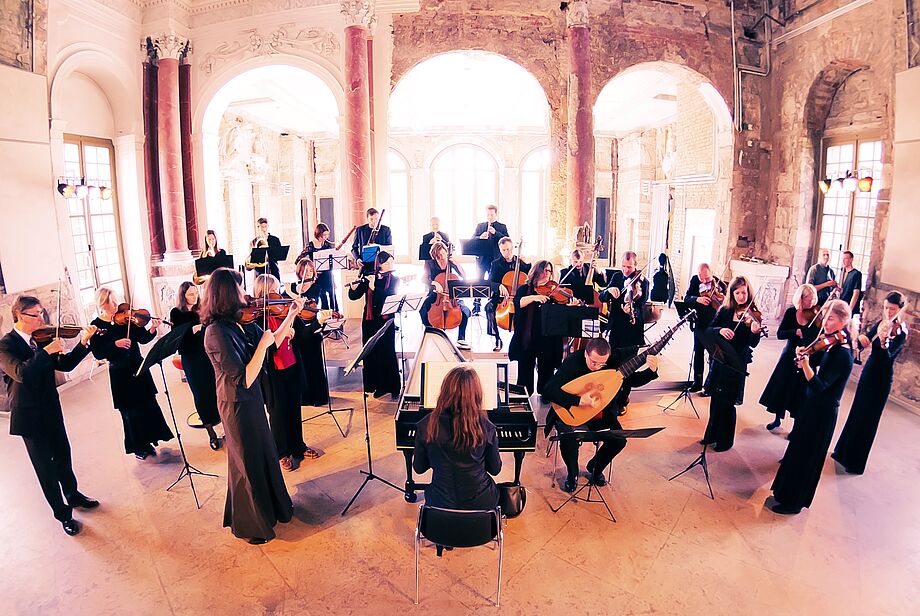 Musikerinnen und Musiker des Dresdner Barockorchesters auf ihre Instrumenten spielend im entkernten Palais im Großen Garten